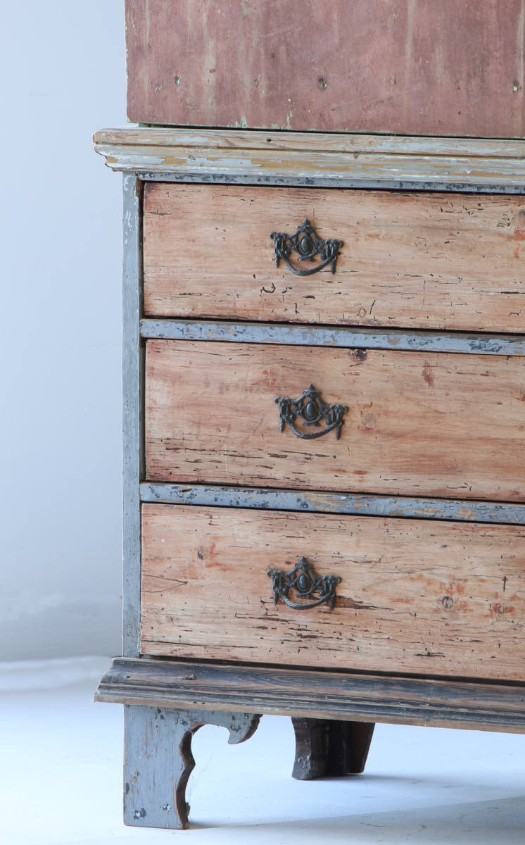 A close up view showing the base and drawers of a painted Dutch cupboard